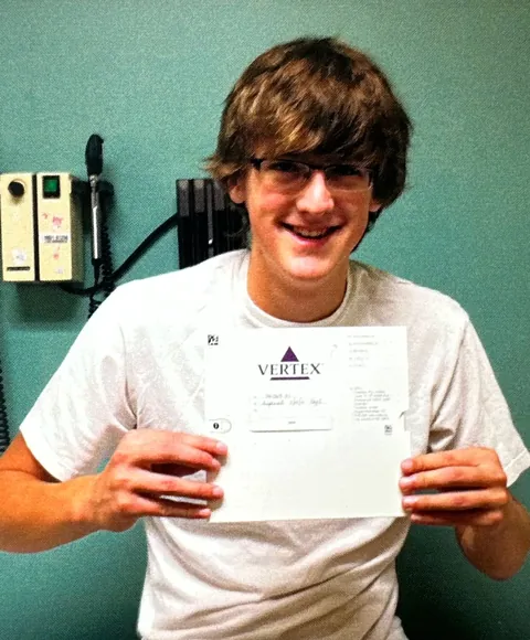 Charlie as a teenager, holding paperwork from an early CFTR-modulator drug trial